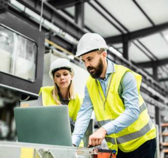 Two people in vests on a worksite who utilize Industrial IT services.
